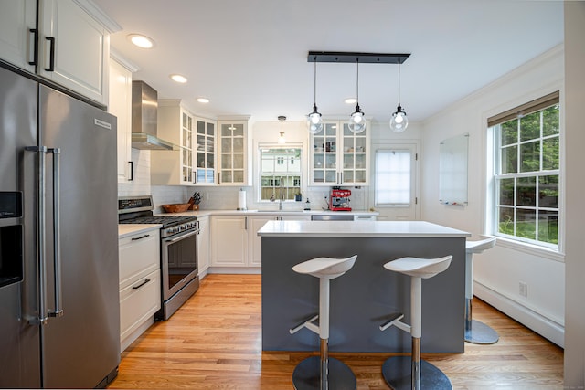 23 Hale St, Westport, CT 06880 - kitchen with stainless steel appliances, a baseboard radiator, light countertops, wall chimney exhaust hood, and tasteful backsplash