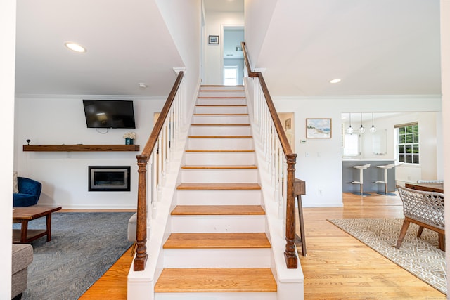 23 Hale St, Westport, CT 06880 - staircase with crown molding, a glass covered fireplace, wood finished floors, recessed lighting, and baseboards