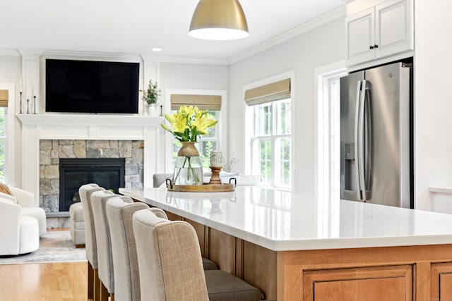 261 W St, Hebron, CT 06248 - kitchen with stainless steel fridge with ice dispenser, healthy amount of natural light, open floor plan, ornamental molding, and light wood finished floors