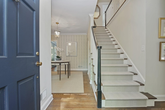 49 Dogwood Ln, New Canaan, CT 06840 - entryway featuring wallpapered walls, wood finished floors, stairway, baseboards, and ornamental molding