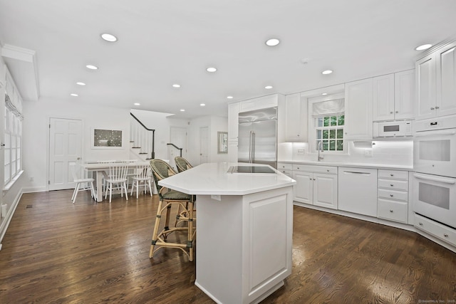 49 Dogwood Ln, New Canaan, CT 06840 - kitchen featuring white appliances, dark wood-style floors, white cabinets, a kitchen island with sink, and recessed lighting