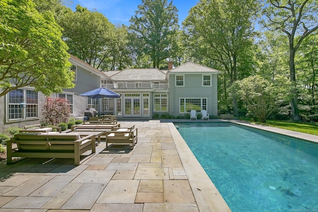 49 Dogwood Ln, New Canaan, CT 06840 - rear view of house featuring an outdoor living space, a patio, french doors, an outdoor pool, and a chimney