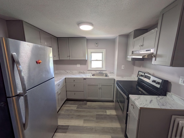 386 Platt Ave, West Haven, CT 06516 - kitchen featuring stainless steel appliances, under cabinet range hood, a sink, a textured ceiling, and wood finished floors
