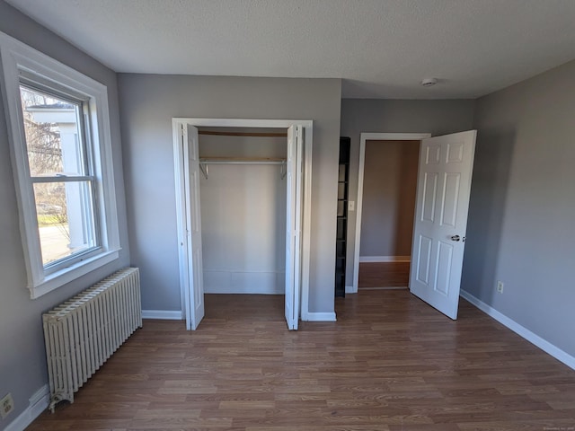 386 Platt Ave, West Haven, CT 06516 - unfurnished bedroom with radiator, wood finished floors, baseboards, and a textured ceiling