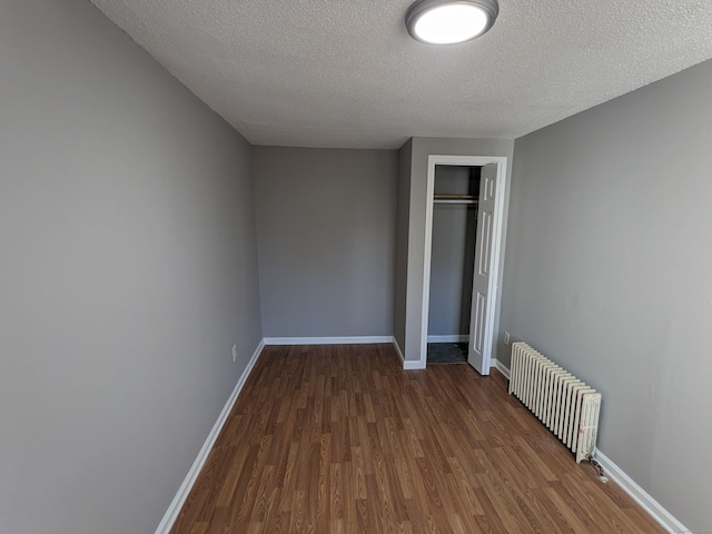 386 Platt Ave, West Haven, CT 06516 - unfurnished bedroom featuring radiator heating unit, wood finished floors, a textured ceiling, and baseboards