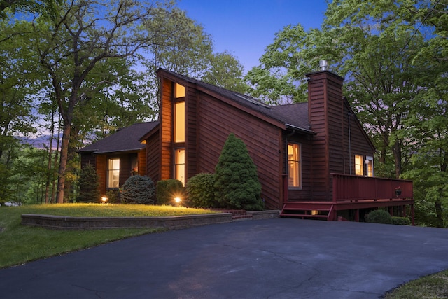 view of side of home featuring a chimney, a wooden deck, and a shingled roof