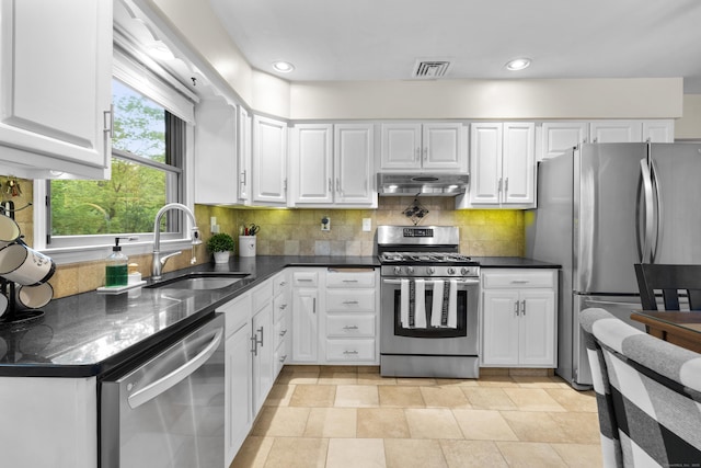 kitchen with appliances with stainless steel finishes, a sink, white cabinets, under cabinet range hood, and recessed lighting