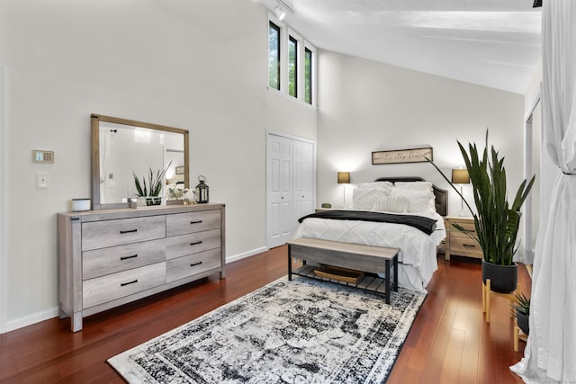 bedroom with dark wood-style flooring, baseboards, high vaulted ceiling, and a closet