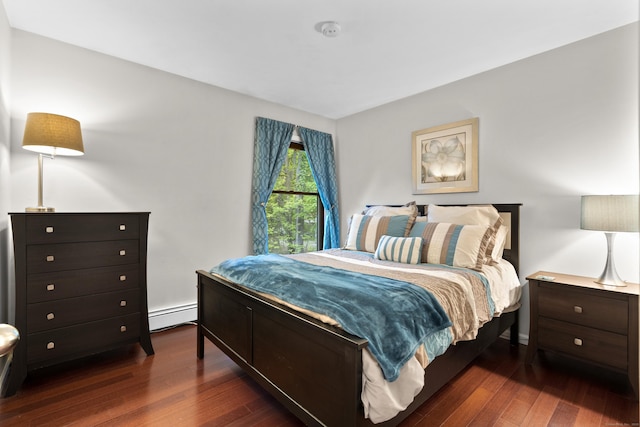 bedroom with a baseboard heating unit and dark wood-style flooring