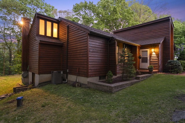 view of front of house featuring a front yard, central AC unit, and roof with shingles