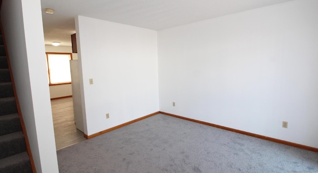 empty room with carpet floors, baseboards, and a smoke detector