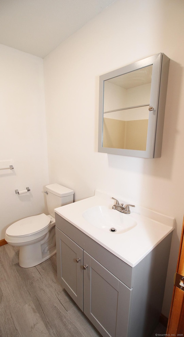 bathroom featuring wood finished floors, toilet, and vanity