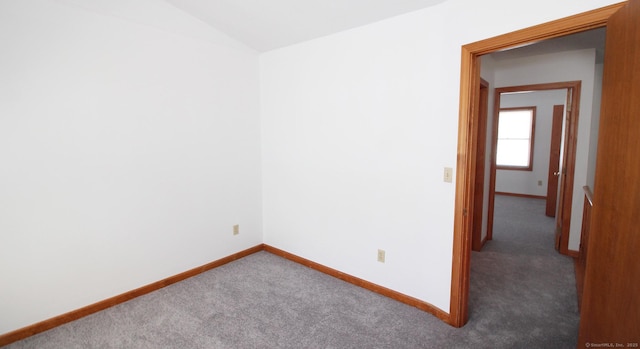 carpeted spare room with baseboards and vaulted ceiling