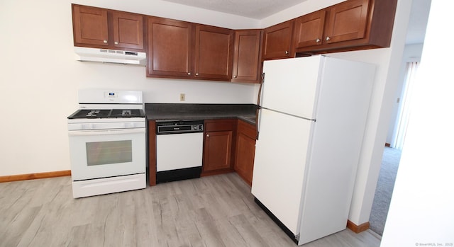 kitchen with under cabinet range hood, white appliances, dark countertops, and light wood finished floors