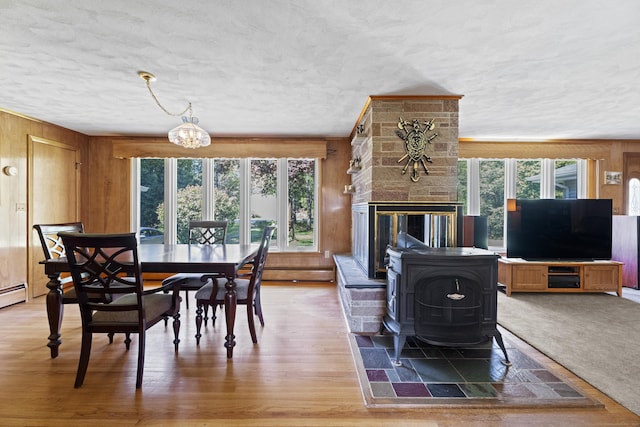 241 Clarks Falls Rd, North Stonington, CT 06359 - dining room with wooden walls, a chandelier, a textured ceiling, a baseboard radiator, and light wood-type flooring