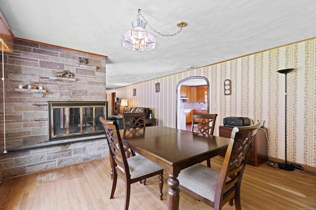 241 Clarks Falls Rd, North Stonington, CT 06359 - dining room featuring wood-type flooring, arched walkways, a stone fireplace, and wallpapered walls