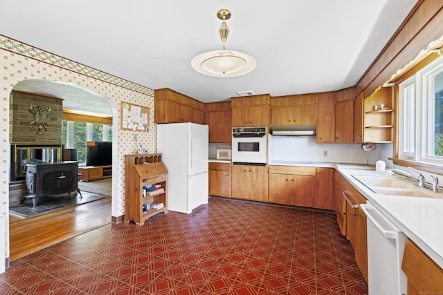 241 Clarks Falls Rd, North Stonington, CT 06359 - kitchen with white appliances, a wood stove, a sink, under cabinet range hood, and plenty of natural light