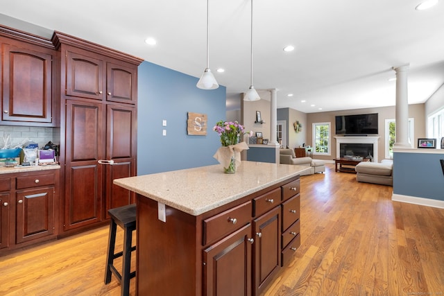 123 Cobblestone Dr, Southington, CT 06479 - kitchen with decorative columns, light wood finished floors, a kitchen island, a glass covered fireplace, and recessed lighting