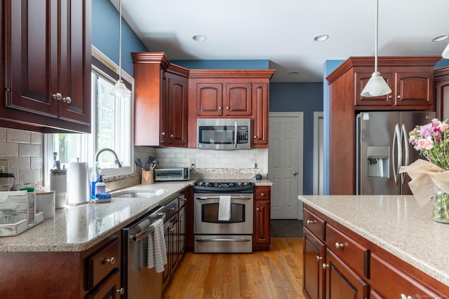123 Cobblestone Dr, Southington, CT 06479 - kitchen featuring stainless steel appliances, a sink, pendant lighting, backsplash, and light wood-type flooring