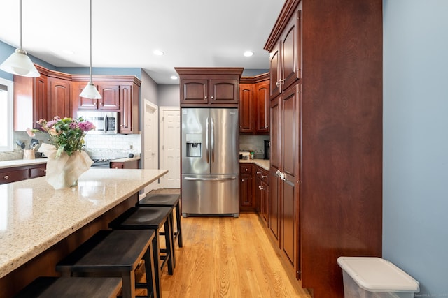 123 Cobblestone Dr, Southington, CT 06479 - kitchen with stainless steel appliances, light wood finished floors, a kitchen bar, decorative backsplash, and recessed lighting