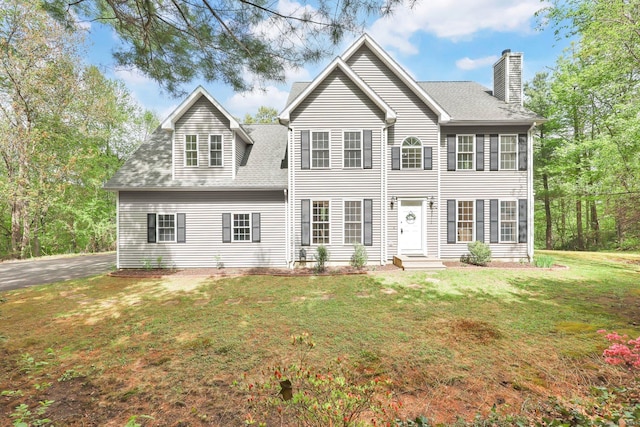view of front of house with a chimney, a front lawn, and roof with shingles
