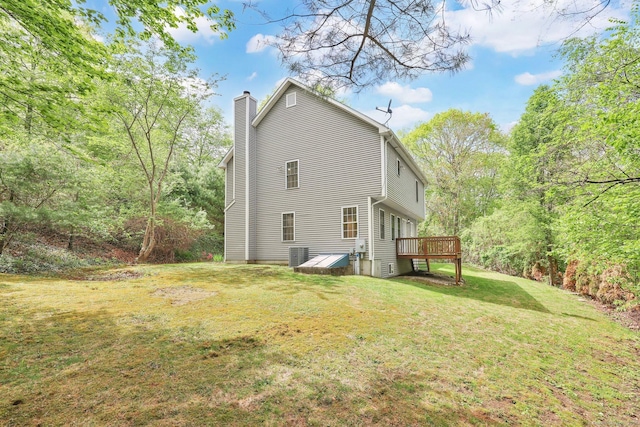 back of house featuring a wooden deck, a chimney, and a lawn