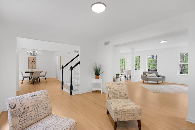 living area with light wood finished floors, stairway, a chandelier, and baseboards