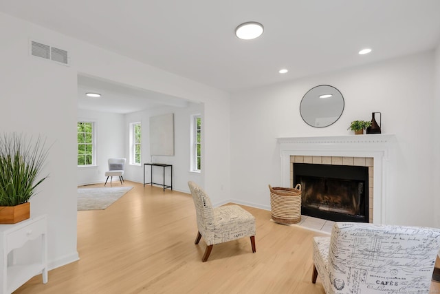sitting room featuring light wood-style floors, a tile fireplace, recessed lighting, and baseboards