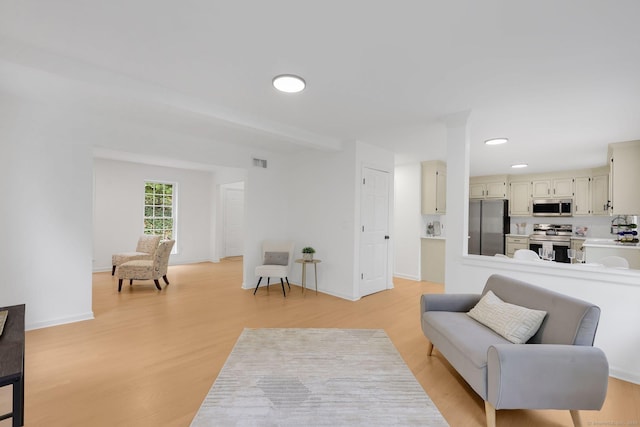 living area featuring light wood-type flooring, recessed lighting, and baseboards