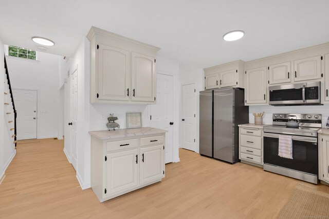 kitchen with stainless steel appliances, light wood-style flooring, tasteful backsplash, and light countertops