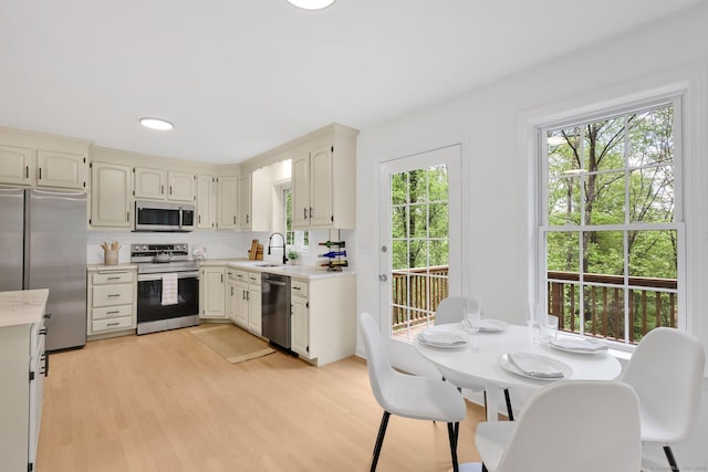 kitchen featuring stainless steel appliances, light countertops, light wood-style flooring, and a sink