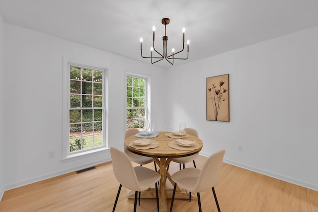 dining space featuring a chandelier, light wood finished floors, and baseboards