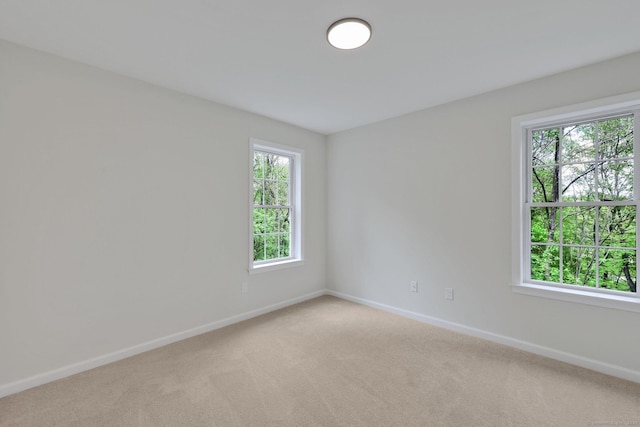 empty room featuring light carpet and baseboards
