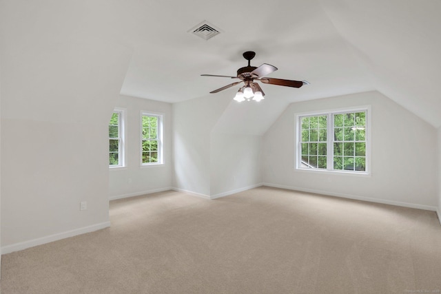 additional living space featuring light carpet, a ceiling fan, plenty of natural light, lofted ceiling, and baseboards