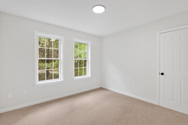 carpeted empty room featuring baseboards