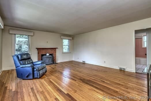 32 Lenox Ave, Norwalk, CT 06854 - unfurnished living room featuring wood finished floors, plenty of natural light, baseboards, and a fireplace
