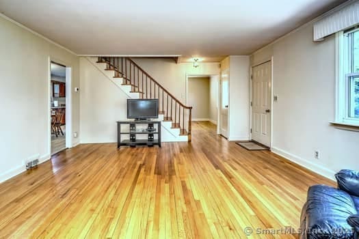 32 Lenox Ave, Norwalk, CT 06854 - unfurnished living room featuring stairs, hardwood / wood-style flooring, ornamental molding, and baseboards