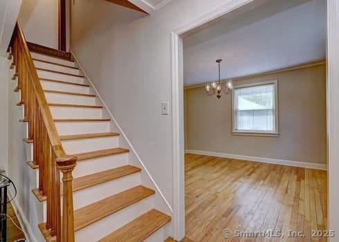 32 Lenox Ave, Norwalk, CT 06854 - staircase featuring wood finished floors, a chandelier, baseboards, and crown molding