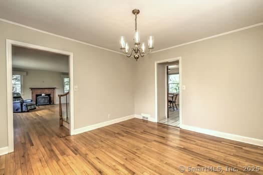 32 Lenox Ave, Norwalk, CT 06854 - empty room with a chandelier, crown molding, healthy amount of natural light, wood finished floors, and baseboards