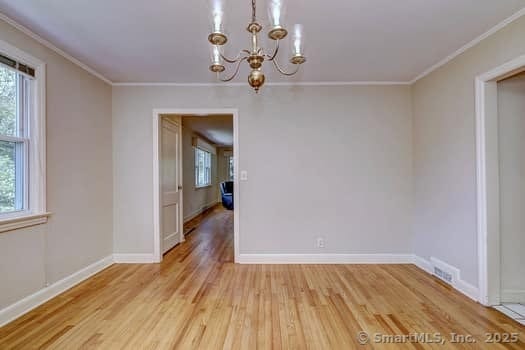 32 Lenox Ave, Norwalk, CT 06854 - unfurnished dining area featuring a chandelier, light wood-style flooring, crown molding, plenty of natural light, and baseboards