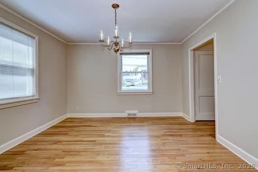 32 Lenox Ave, Norwalk, CT 06854 - spare room with crown molding, a chandelier, plenty of natural light, light wood-style flooring, and baseboards