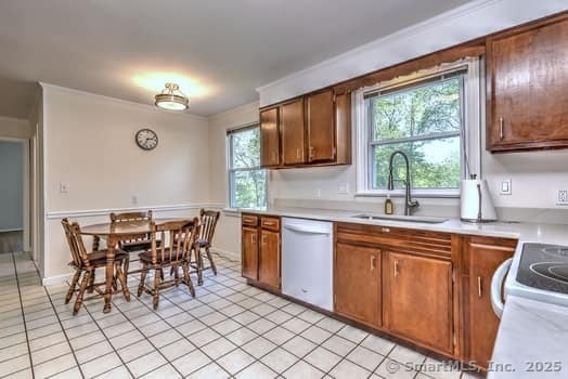32 Lenox Ave, Norwalk, CT 06854 - kitchen with dishwasher, a sink, light countertops, light tile patterned flooring, and crown molding