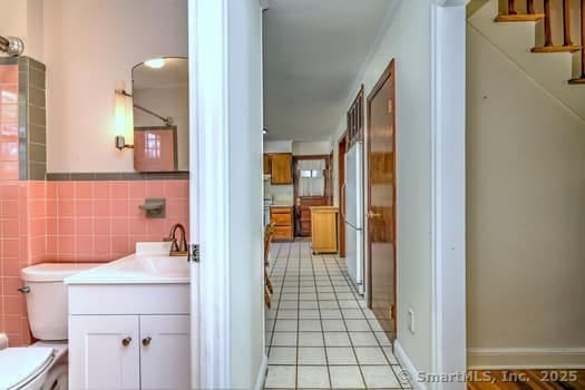 32 Lenox Ave, Norwalk, CT 06854 - bathroom with toilet, tile patterned floors, tile walls, vanity, and wainscoting