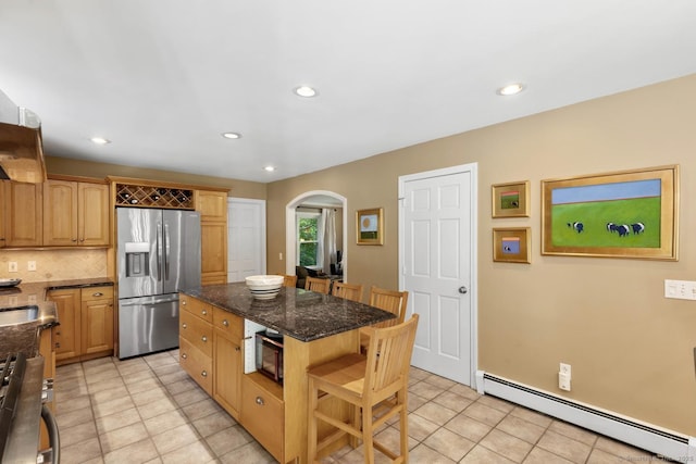 15 Westwood Rd, Essex, CT 06442 - kitchen featuring appliances with stainless steel finishes, baseboard heating, arched walkways, light tile patterned flooring, and dark stone countertops