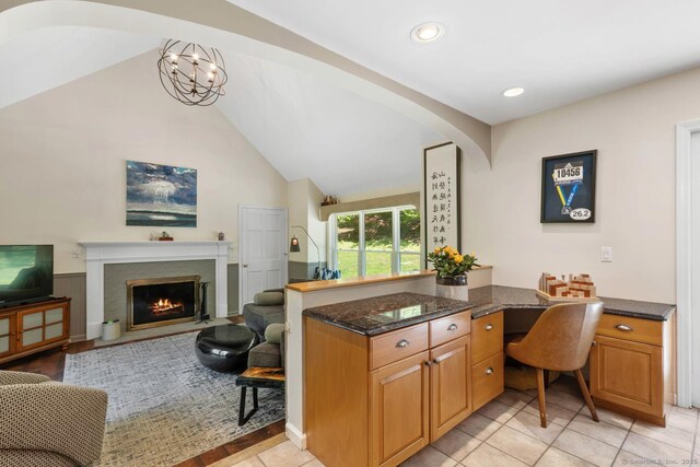15 Westwood Rd, Essex, CT 06442 - kitchen with vaulted ceiling, dark stone counters, a desk, a fireplace with flush hearth, and arched walkways