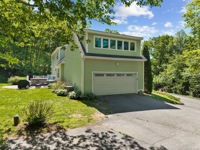 15 Westwood Rd, Essex, CT 06442 - view of front facade with a garage, driveway, a front lawn, and central AC unit