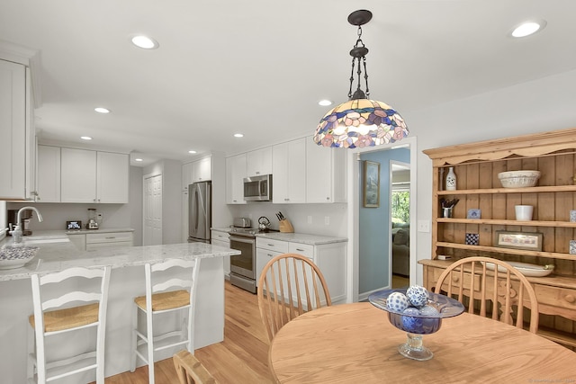95 Vista Rd, Wilton, CT 06897 - kitchen featuring appliances with stainless steel finishes, a sink, light wood finished floors, a peninsula, and white cabinetry