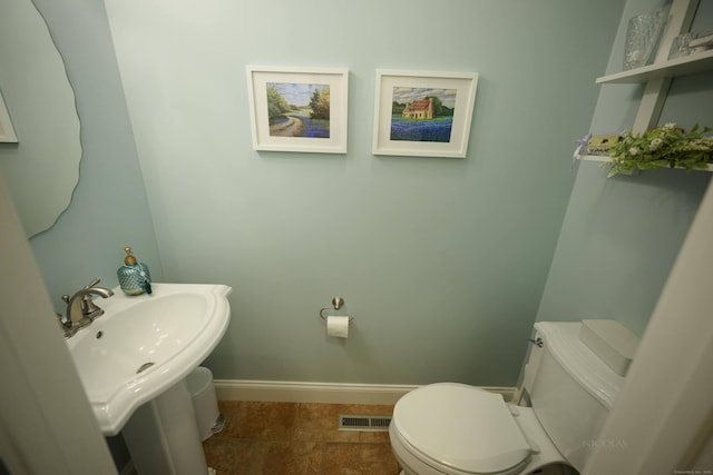 bathroom featuring toilet, baseboards, and a sink