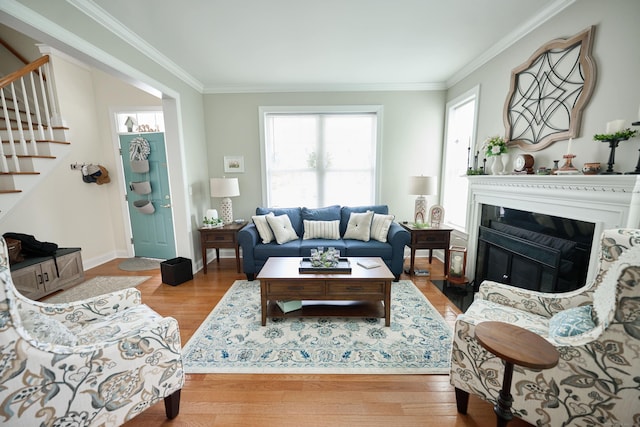 living room with stairway, wood finished floors, ornamental molding, a fireplace with flush hearth, and baseboards