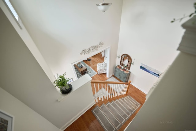 staircase featuring a high ceiling, wood finished floors, and baseboards